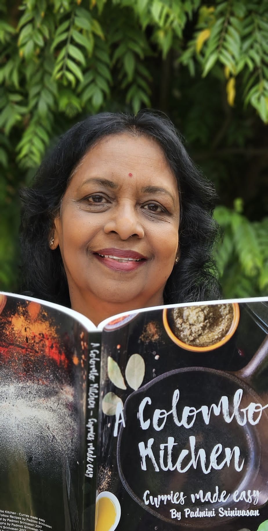 Padmini Srinivasan holding A Colombo Kitchen cookbook